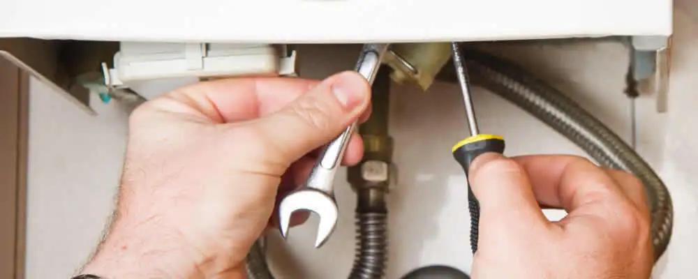 Boiler repair technician tightening pipe fittings and connections in Scottsdale, AZ