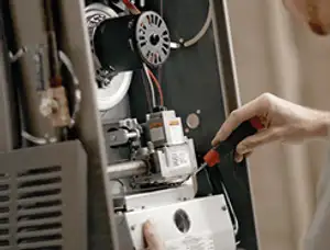 Furnace repair technician inspecting internal components and wiring in Scottsdale, AZ