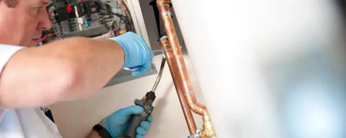 Water heater repair technician testing copper pipe connections and controls in Scottsdale, AZ
